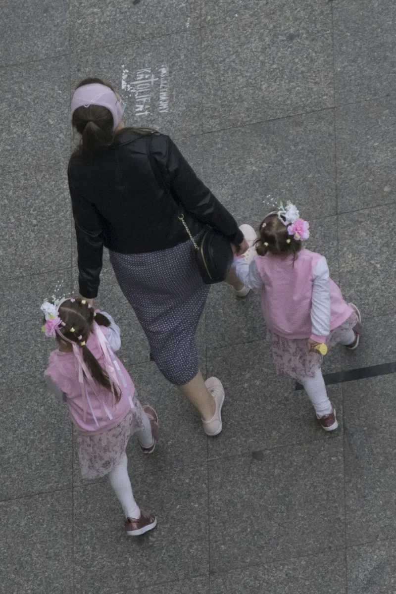 Woman holding hands with two little girls dressed in pink and floral headbands